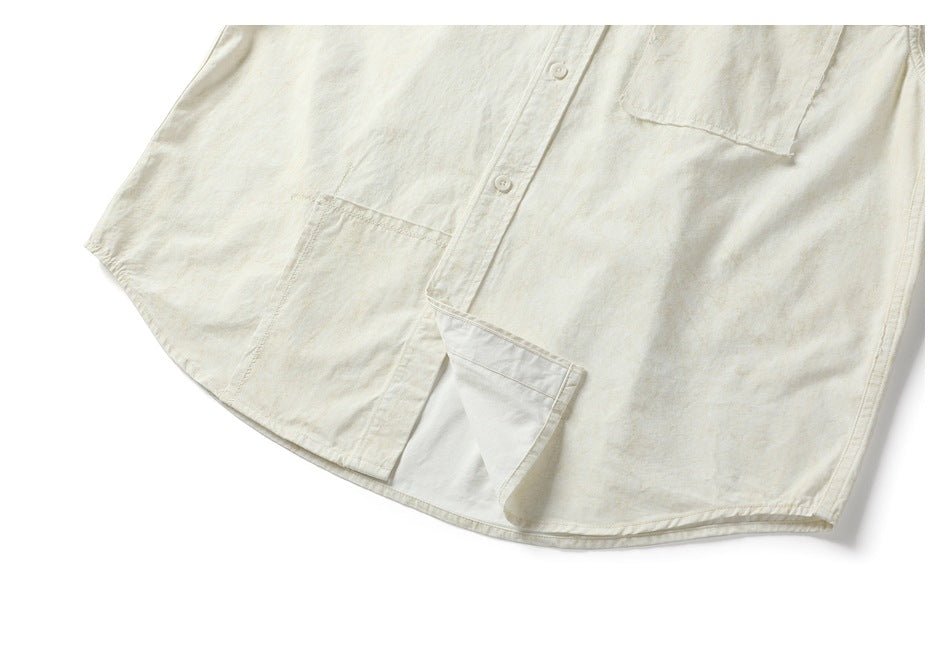 Lower front of the off-white shirt, showing its curved hem, placket, and chest pocket.