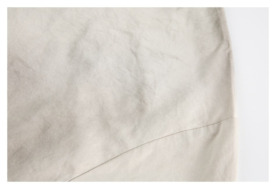 Close-up of a light beige garment panel with a diagonal seam and subtle creasing.