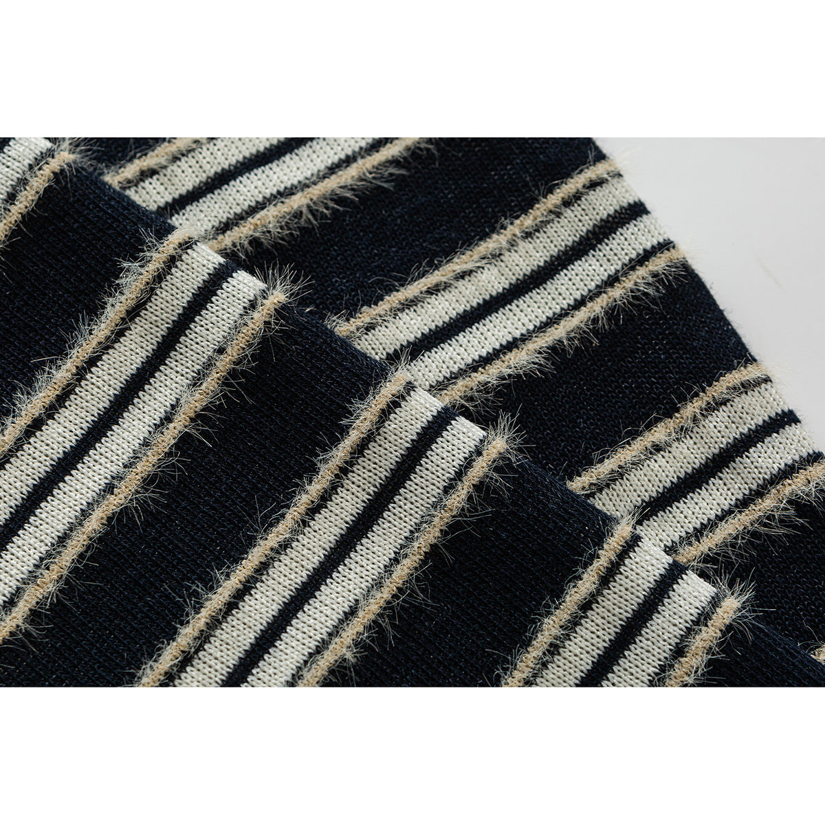 Close-up of black and cream striped knit with fuzzy beige yarn accents.
