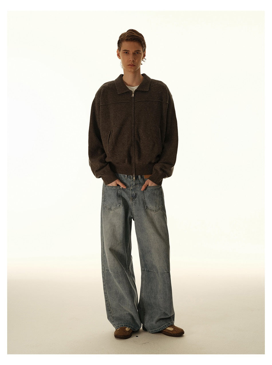 Person wearing wide-leg faded blue jeans with a brown zip-up knit top and brown shoes, full-length front view