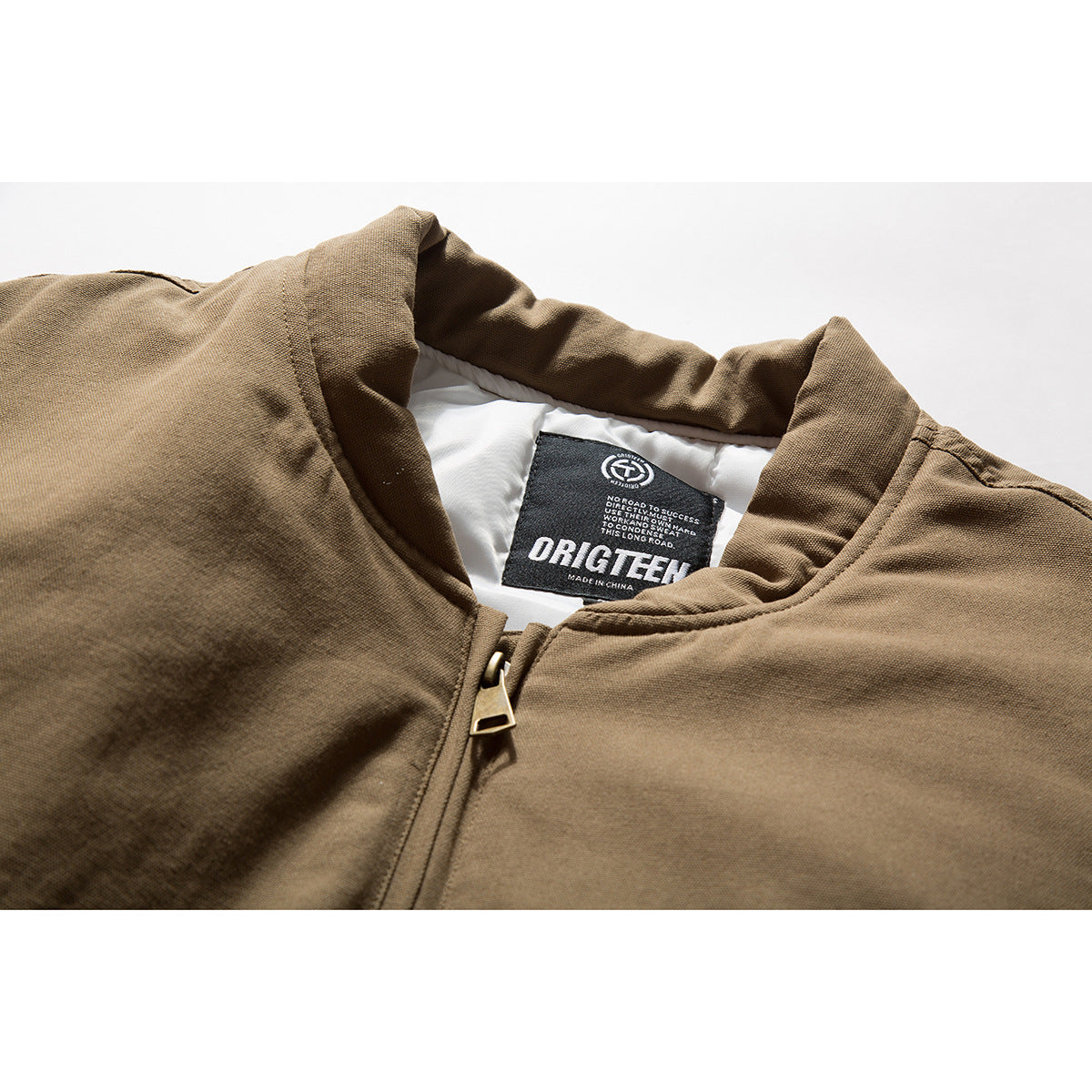 Close-up of a brown jacket collar, zipper pull, white lining, and black neck label.