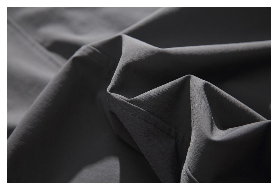 Extreme close-up of charcoal gray garment fabric folded to show its surface and stitching.