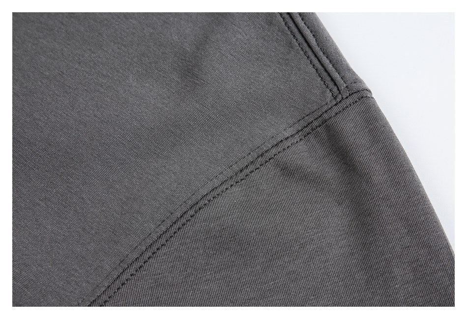Close-up of charcoal garment fabric with a curved stitched seam and a ribbed panel.