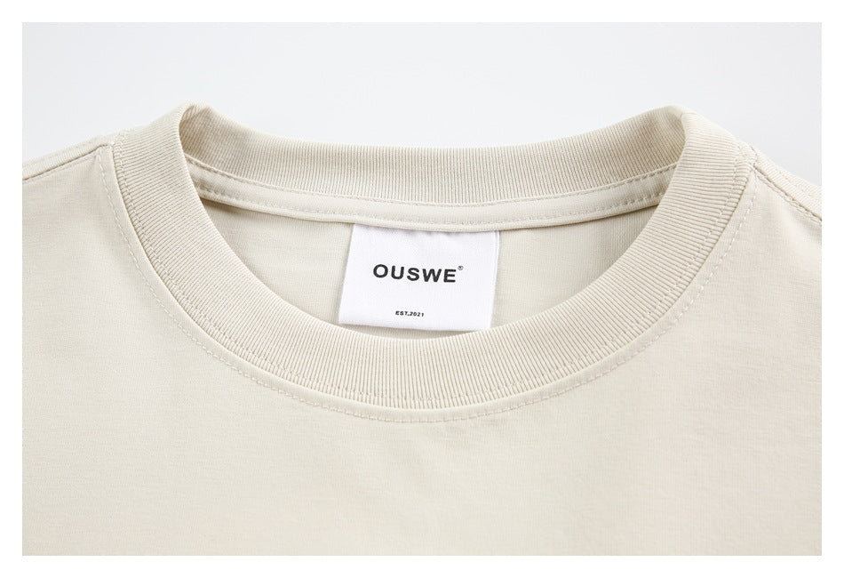 Close-up of a cream T-shirt's ribbed crew neck, seams, and OUSWE label.