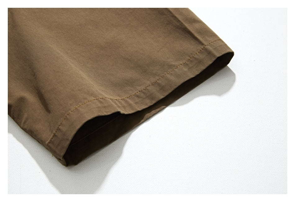 Close-up of a brown garment edge with a curved stitched hem against a white background.