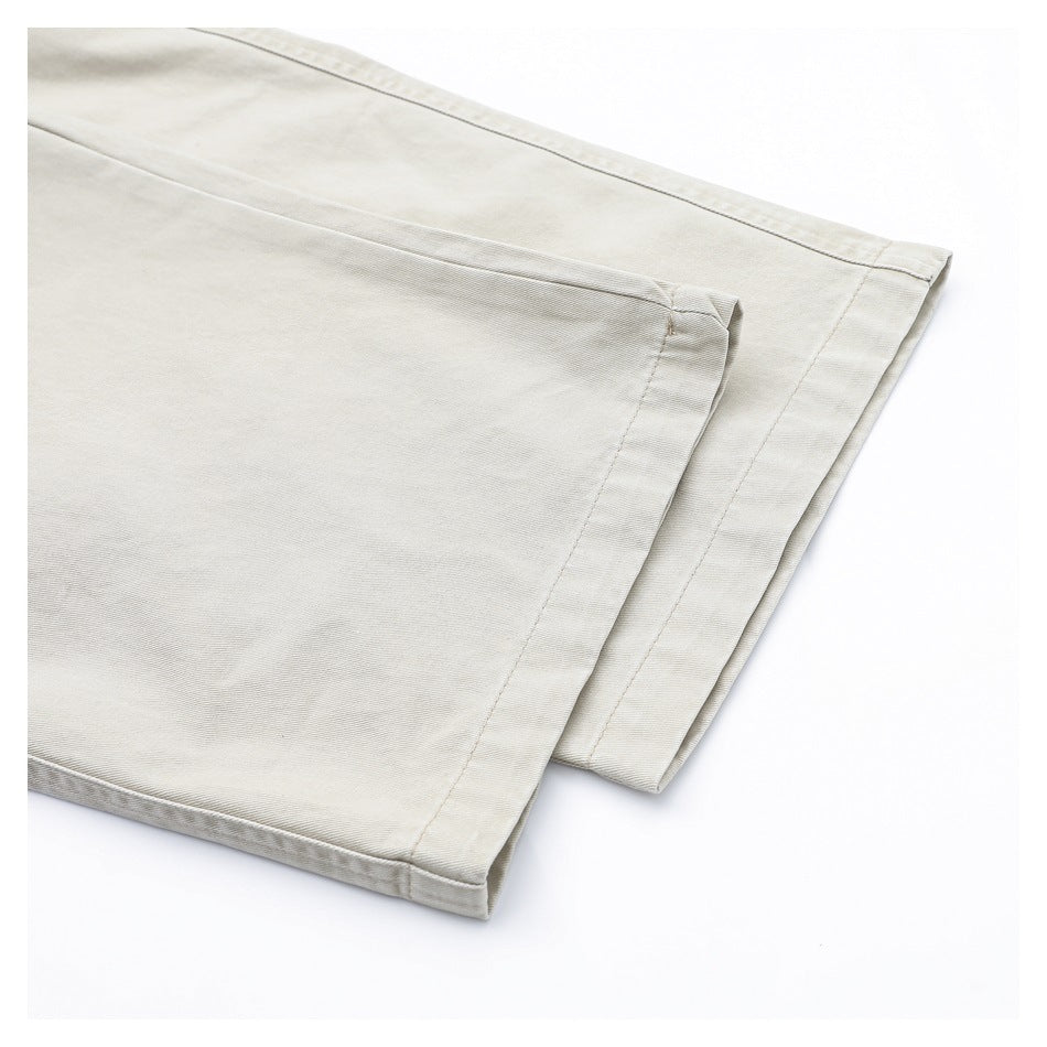 Close-up of the wide leg openings and stitched hems of light beige pants.
