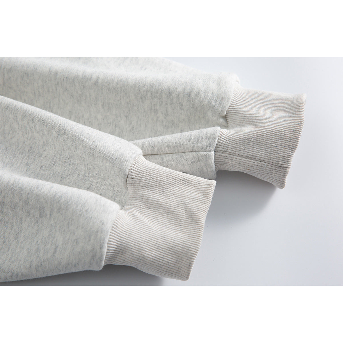 Close-up of the light gray marl hoodie’s sleeves and wide ribbed cuffs.