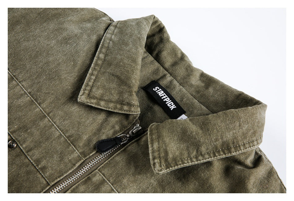 Close-up of an olive-brown jacket collar, metal zipper, stitching, and sewn neck label.