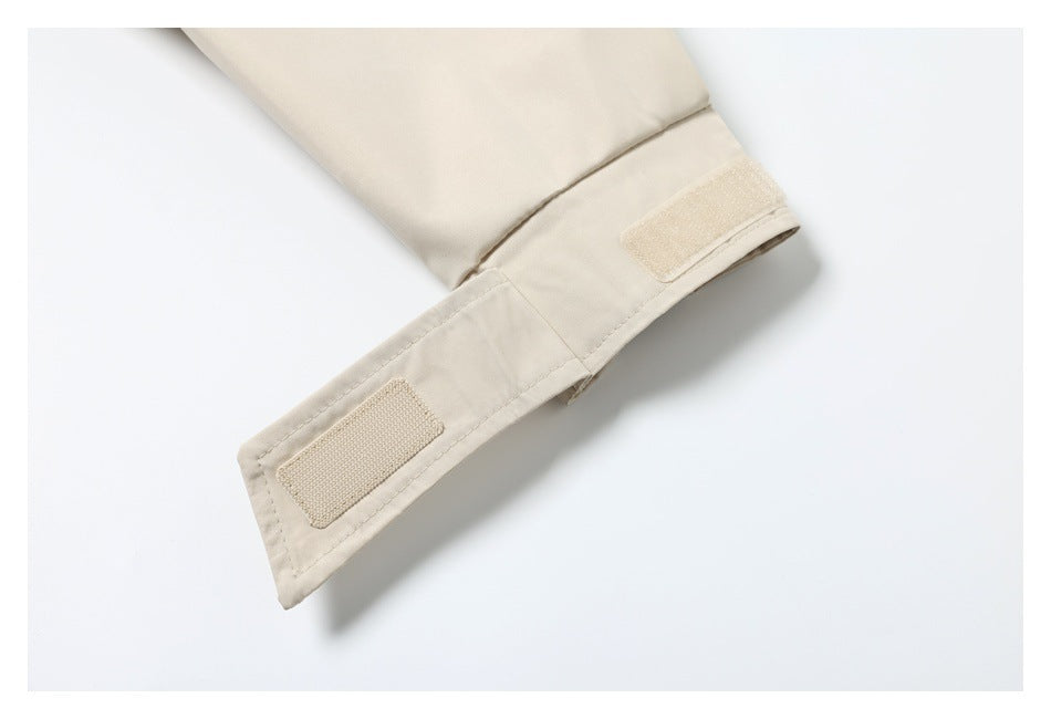 Close-up of a beige garment sleeve with an adjustable hook-and-loop cuff tab.