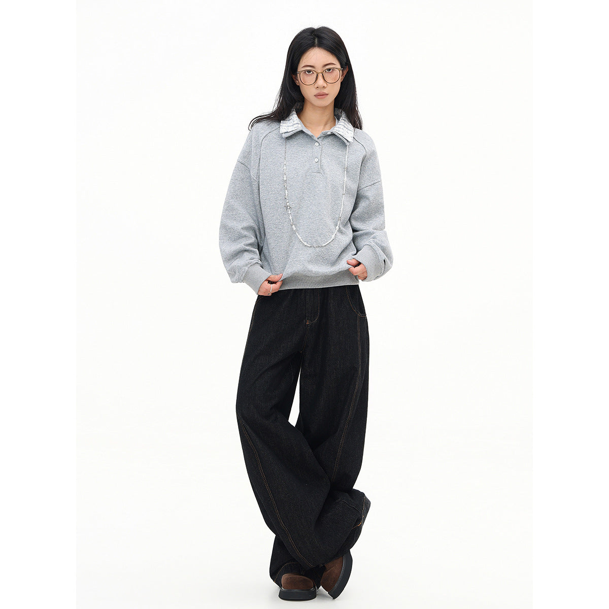 Model wearing an oversized light gray pullover with a striped collar and black wide-leg jeans.