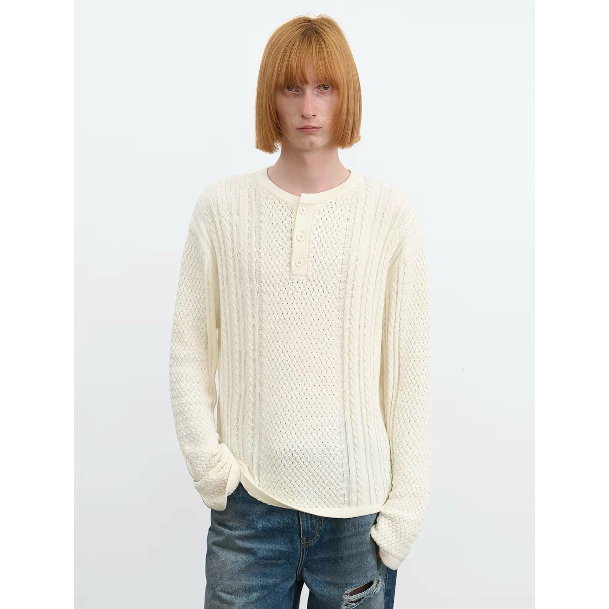 Front view of a model in an ivory cable-and-texture knit pullover with a three-button placket.