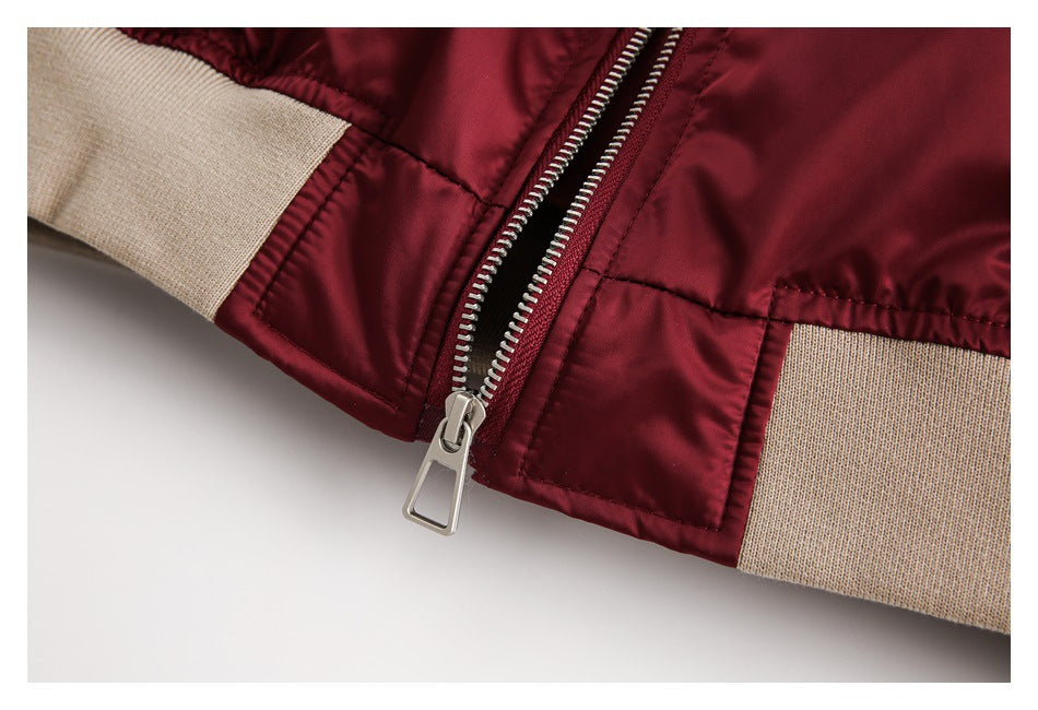 Close-up of the burgundy jacket's silver front zipper and beige ribbed hem.
