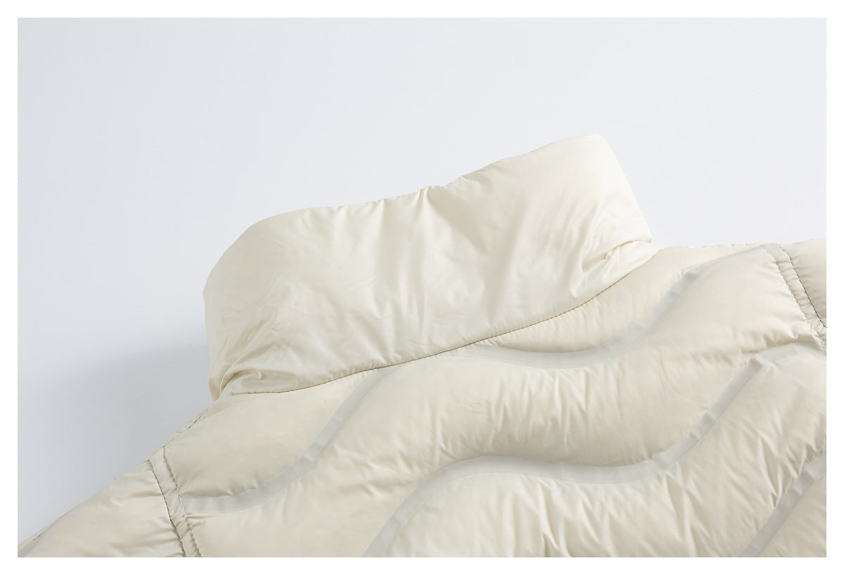 Close-up of an ivory puffer jacket's raised collar and curved gray-piped quilting.