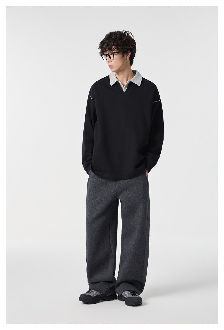 Model wearing a black long-sleeve top with a light gray collar and stitched shoulder accents.