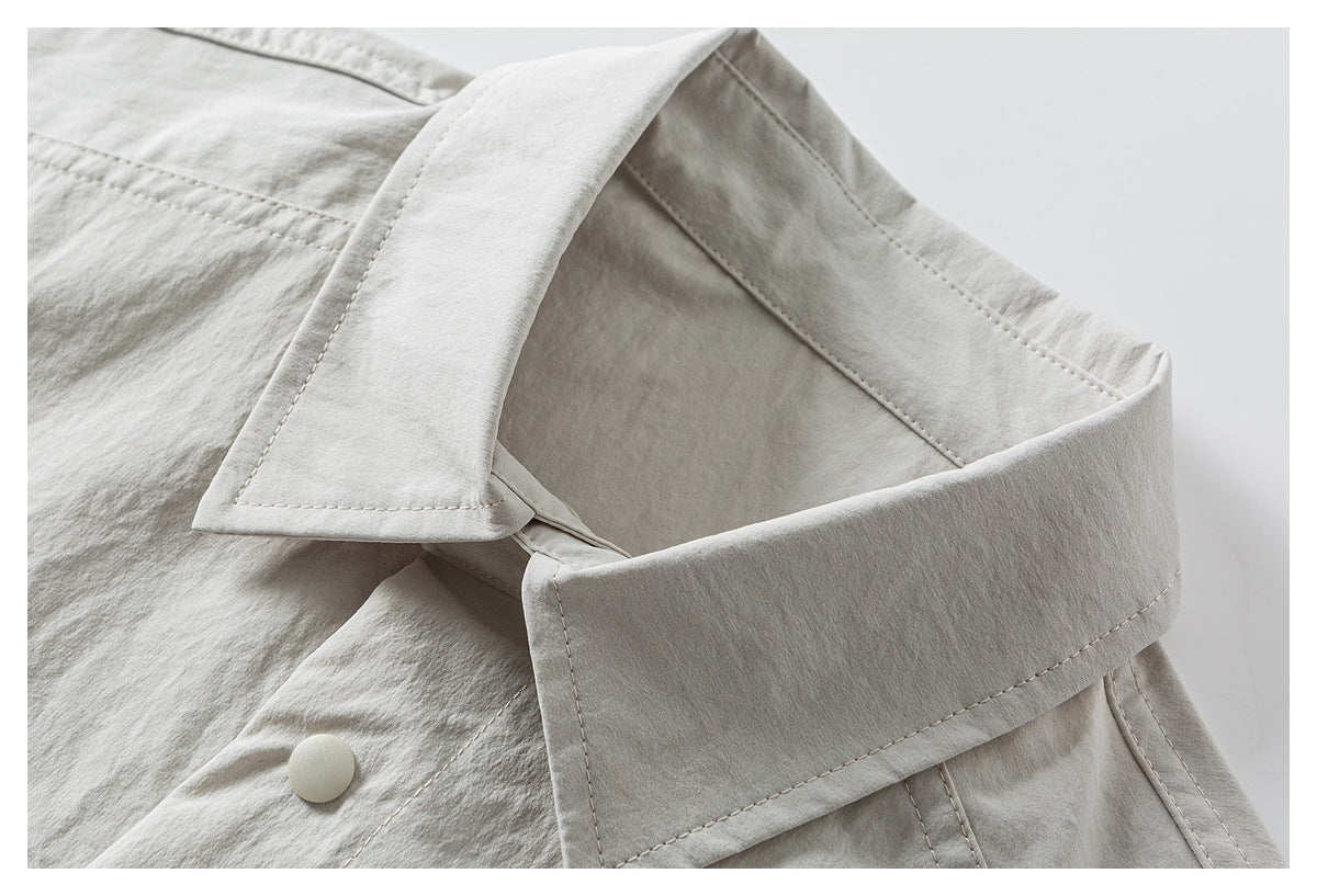 Close-up of a light gray-beige garment collar, stitching, and a pale button.