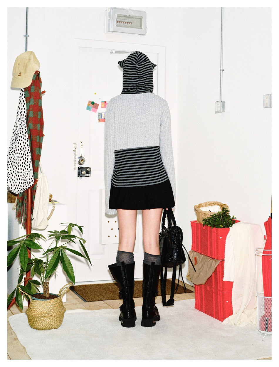 Rear view of a model wearing a gray and black striped hooded top with a gray back panel and black skirt.