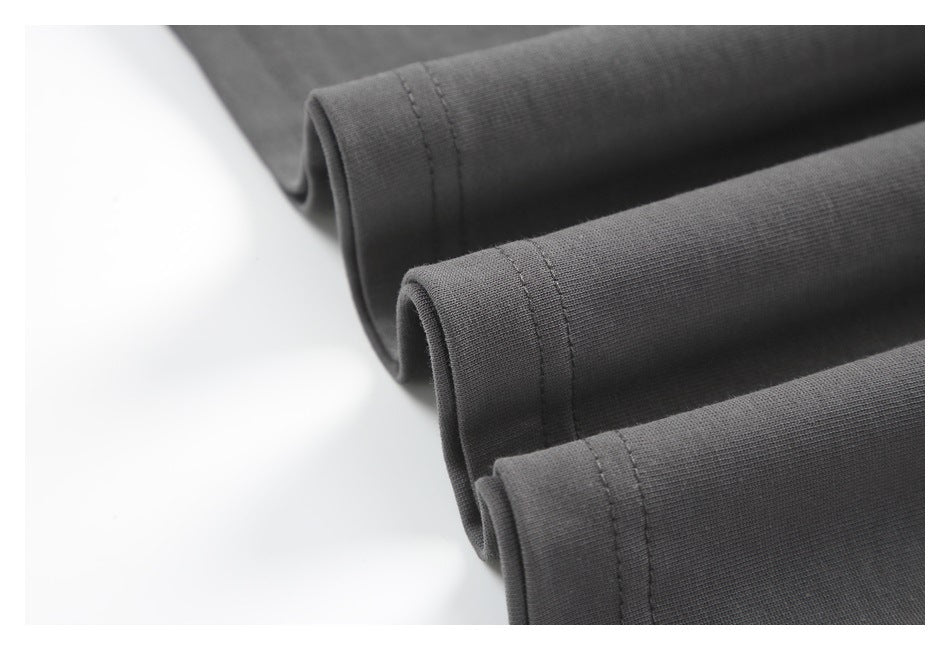 Close-up of three folded edges of dark charcoal fabric with parallel stitching.