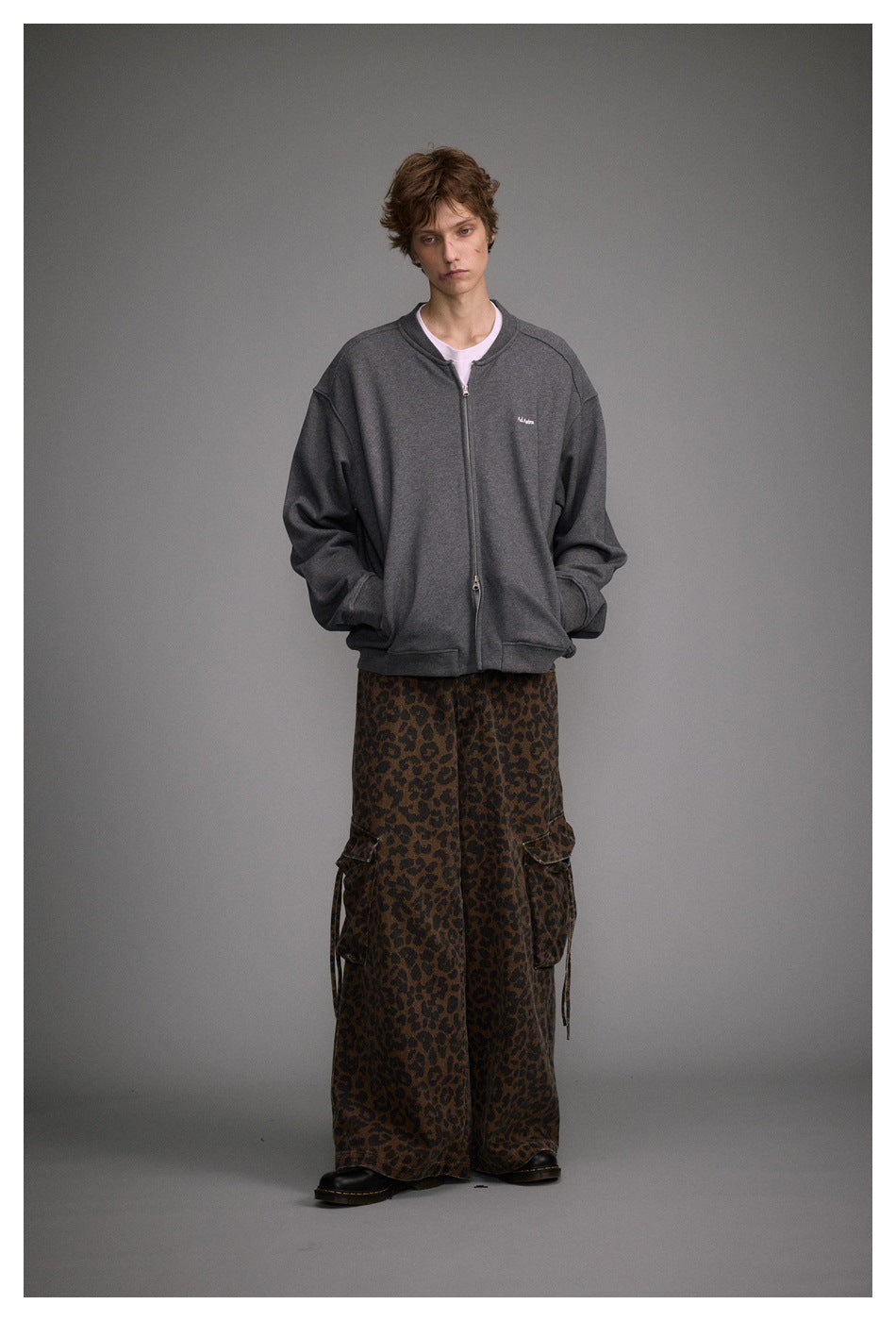 Full-length model wearing a charcoal gray zip-front jacket and wide-leg brown leopard-print cargo pants.