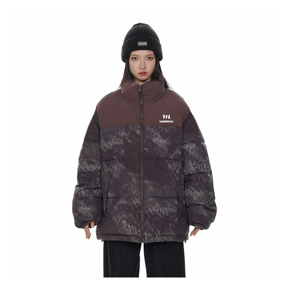 Model wearing a dark plum and charcoal mottled puffer jacket with a high collar and front zip.