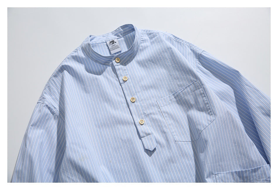 Close front view of a light blue pinstriped shirt showing its band collar, short button placket, and chest pocket.