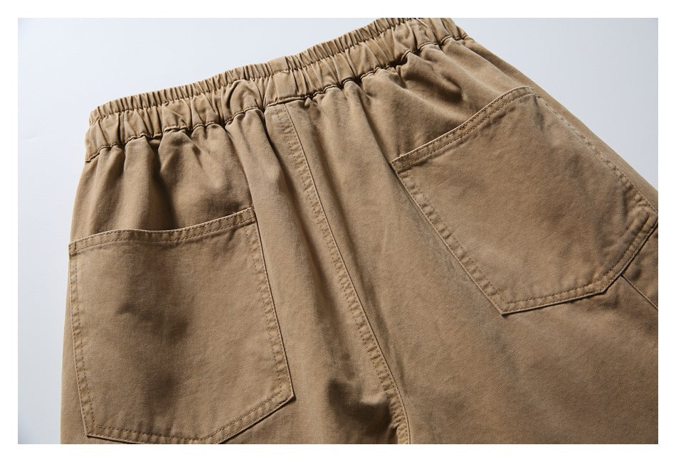 Partial rear view of tan bottoms with a gathered elastic waistband and two patch pockets.