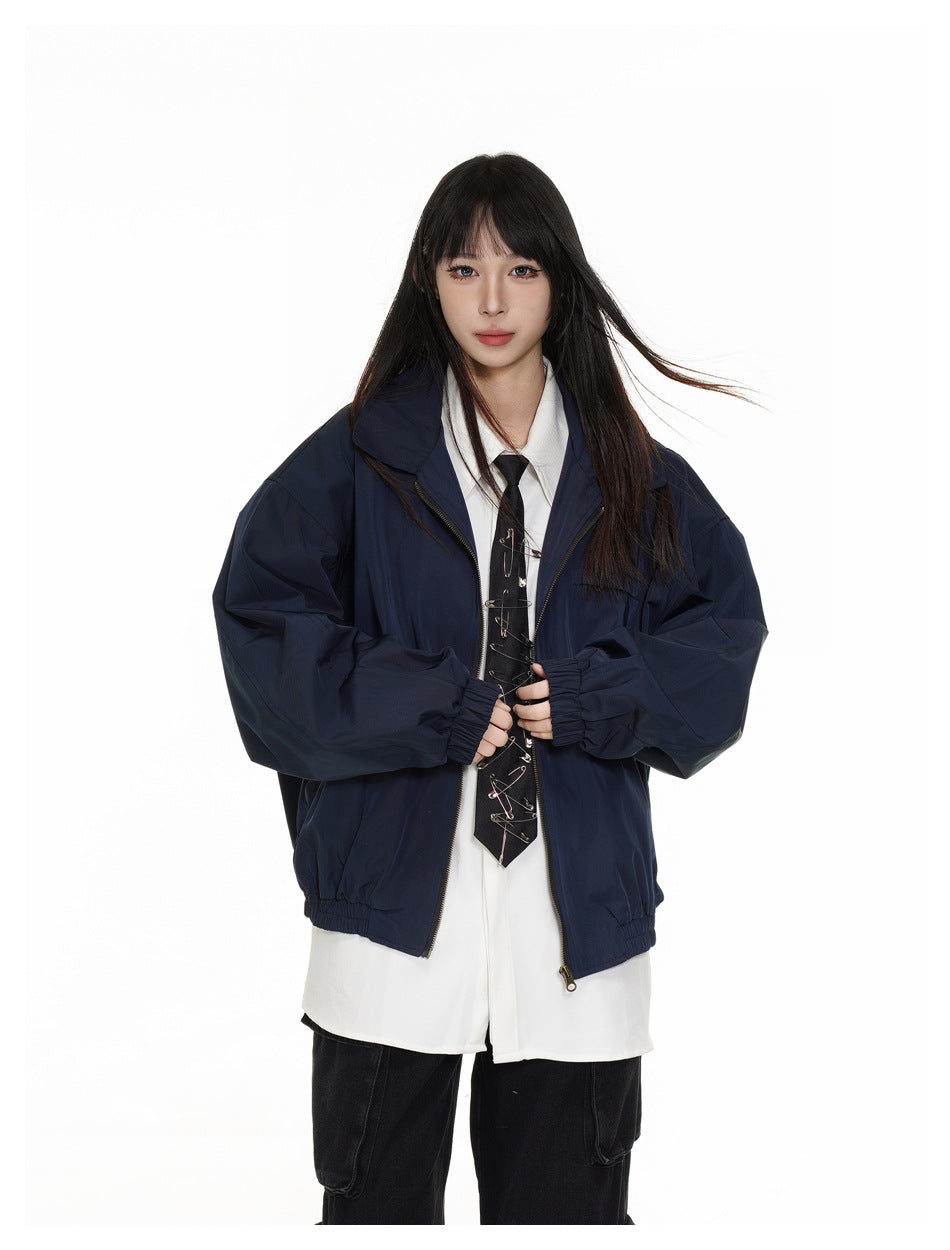 Closer front view of a model wearing an open navy jacket over a white shirt and black tie.