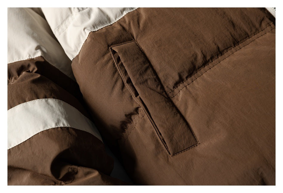 Close-up of a brown jacket with a cream color-blocked section and a vertical pocket.