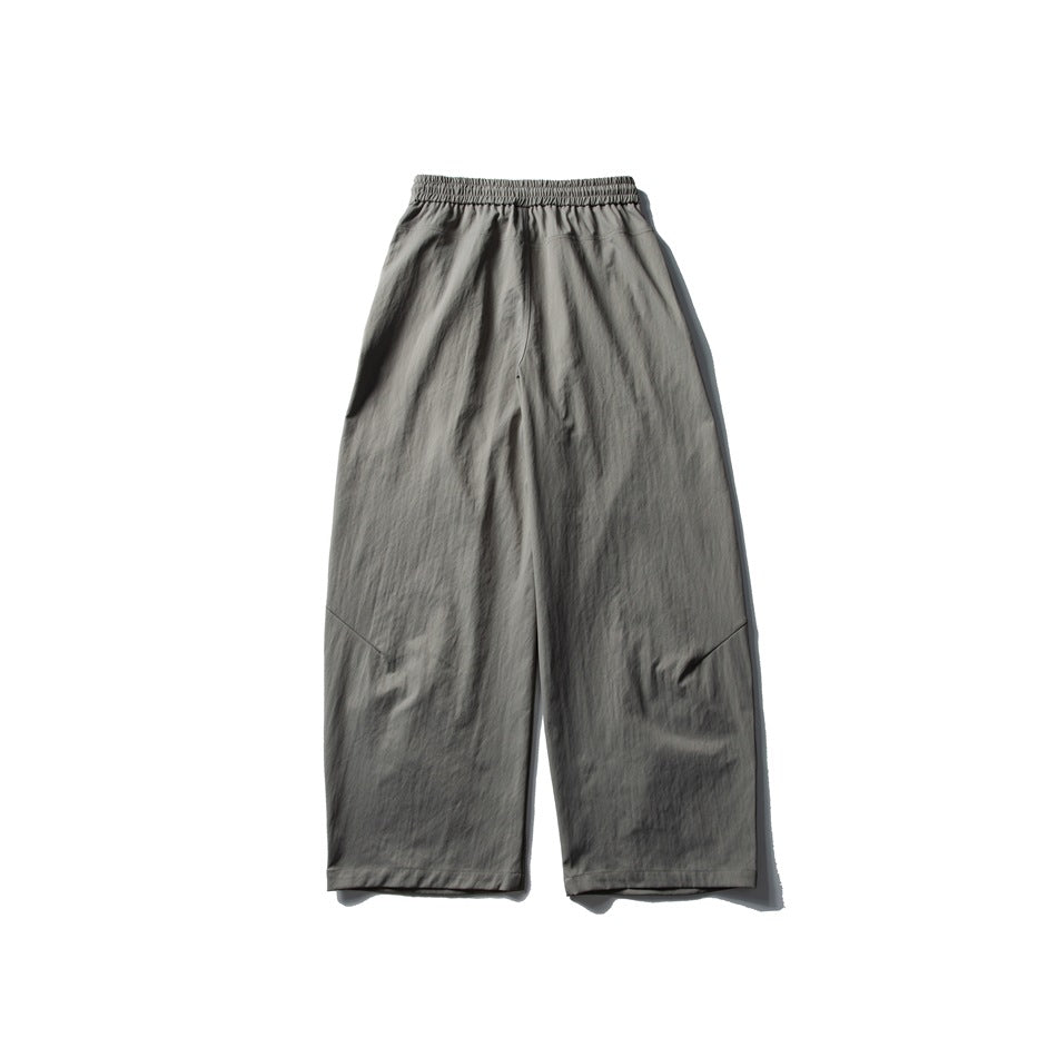 Back view of gray wide-leg trousers laid flat, with an elastic waistband and stitched knee details.