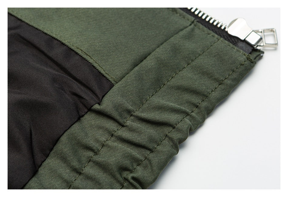 Close-up of olive garment construction with black lining, stitched seams, and a silver zipper.