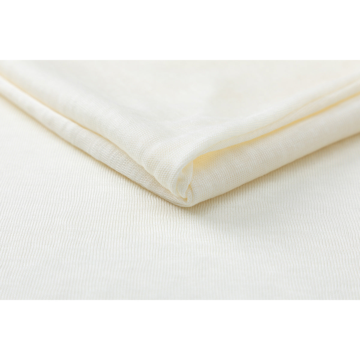 Close-up of folded off-white shirt fabric showing its fine surface texture.