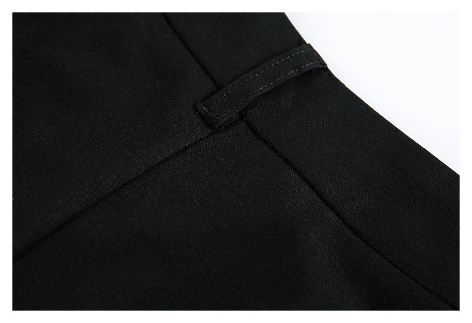 Close-up of a small adjustment tab and seam on black trousers.