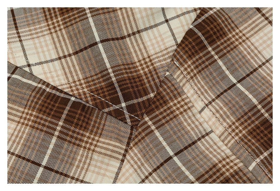 Close-up of brown and cream plaid shirt fabric and intersecting stitched seams.