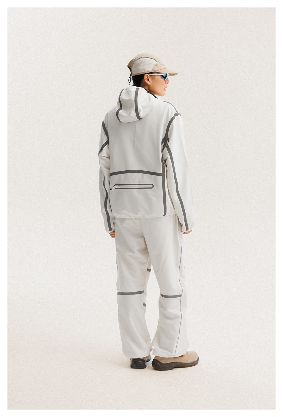 Rear view of a model wearing a white hooded jacket with gray piping and matching pants.