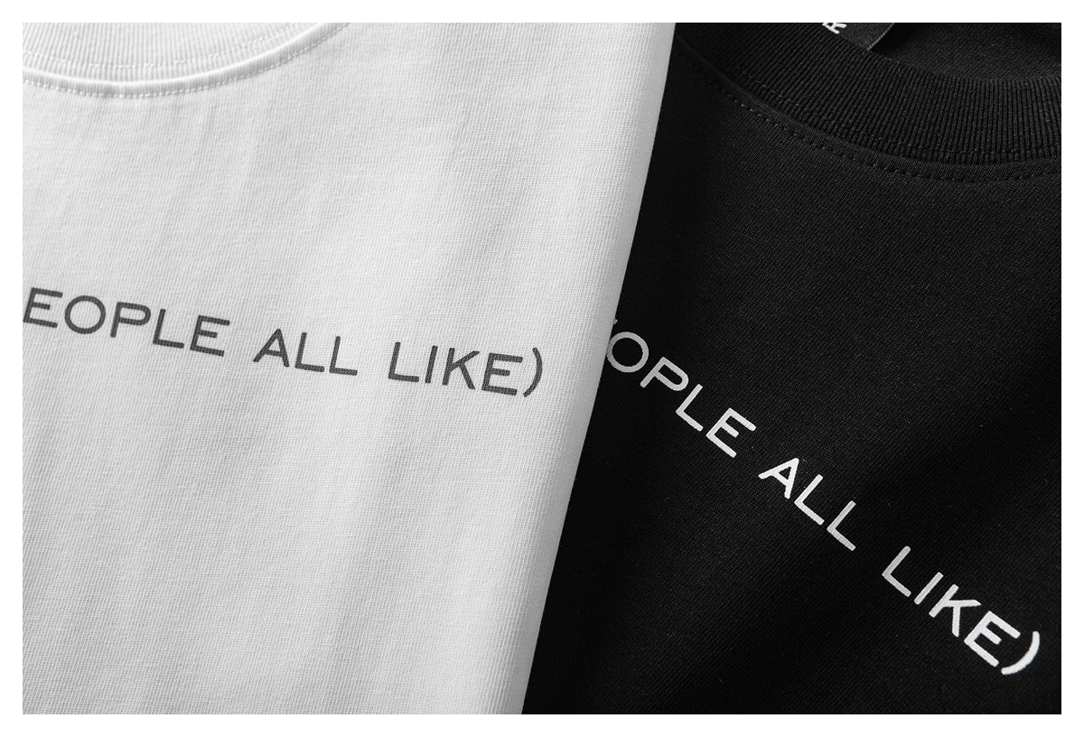 Close-up of white and black T-shirts with partial English lettering and ribbed crew necks.