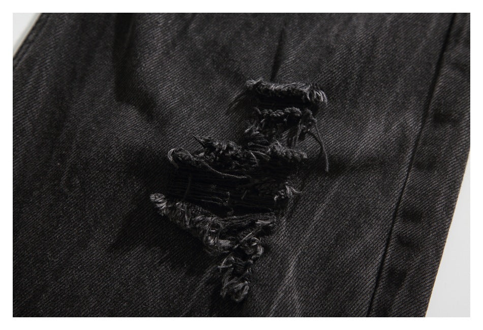 Close-up of several frayed tears in black denim.
