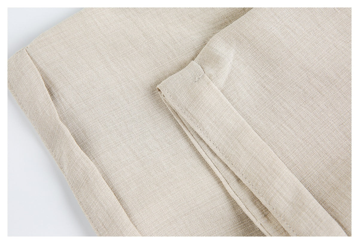 Close-up of a folded edge and stitched detail on beige garment fabric.