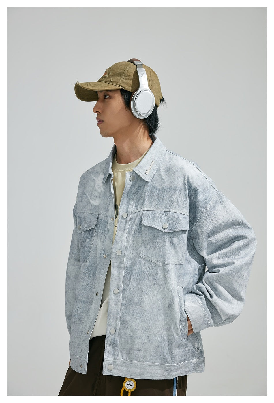 Three-quarter front view of a model wearing a light gray mottled jacket with snap closures and two flap chest pockets.