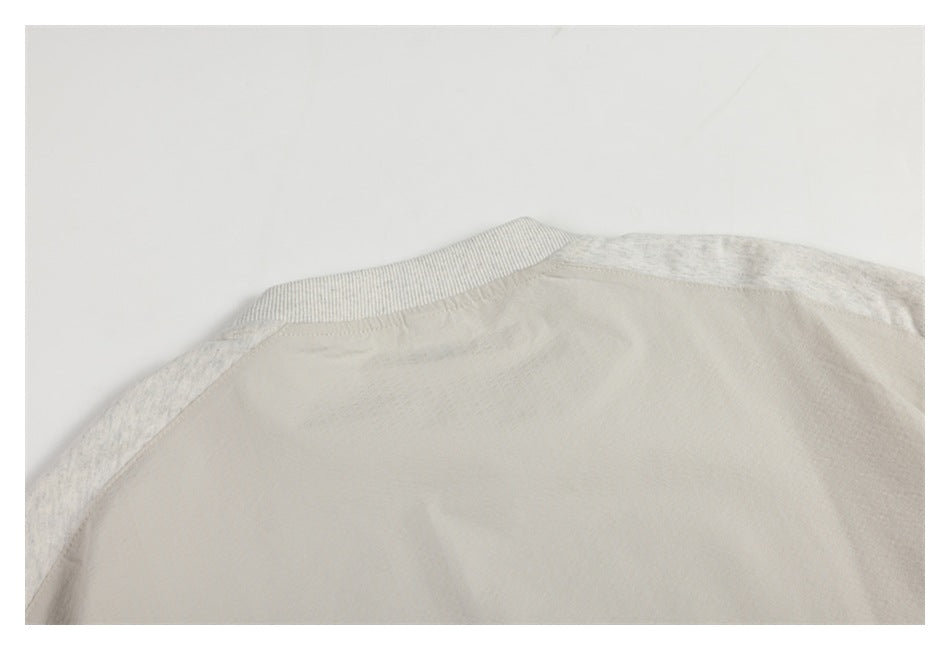 Close-up of the back neckline and shoulder seams of a pale heather-gray garment.