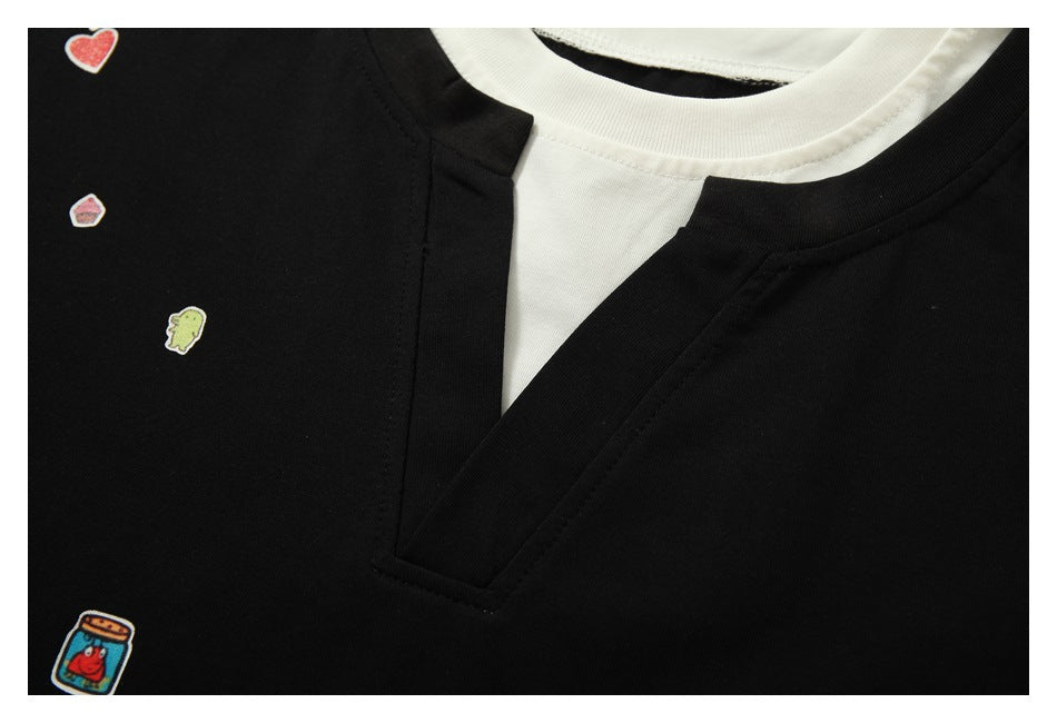 Close-up of a black shirt's V-slit neckline layered over a white crew neck, with small colorful patches.