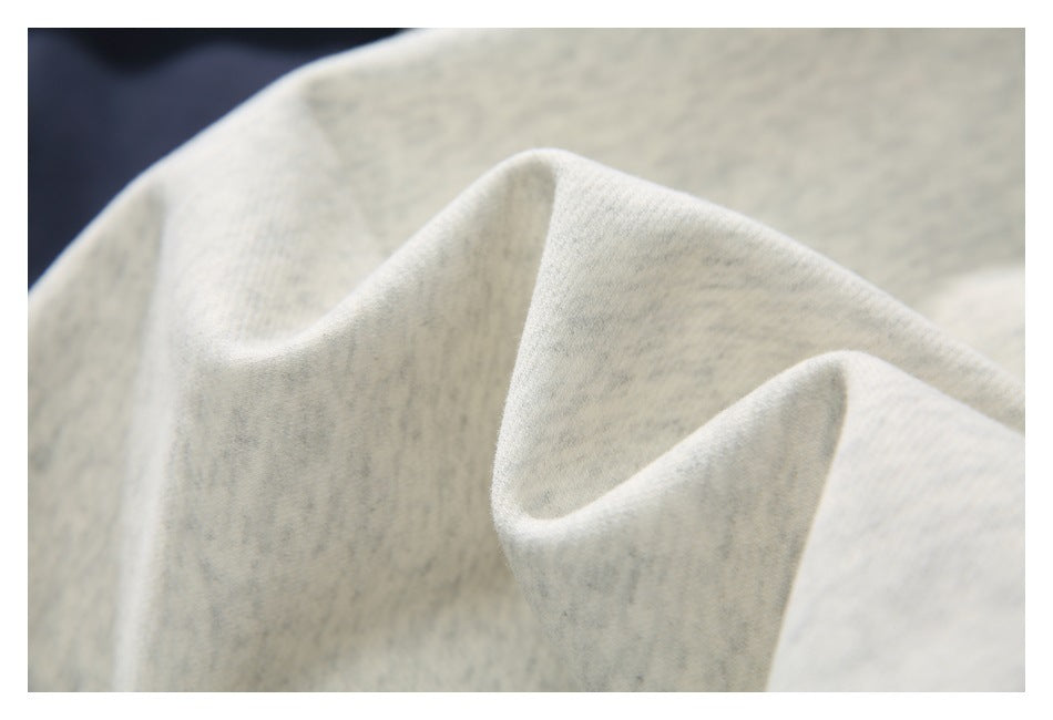 Close-up of the light gray heather sweatshirt fabric draped to show its surface and folds.