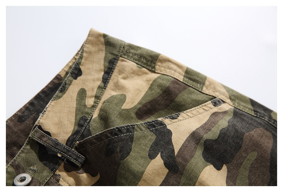 Close-up of camouflage trousers showing a stitched waistband and pocket opening.