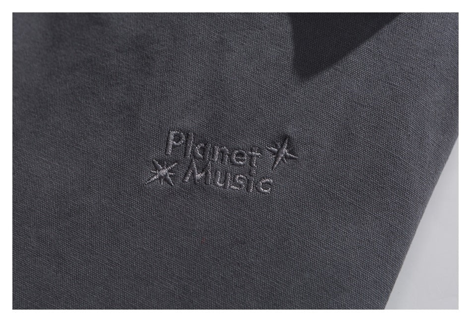 Close-up of embroidered English lettering and star motifs on charcoal jacket fabric.