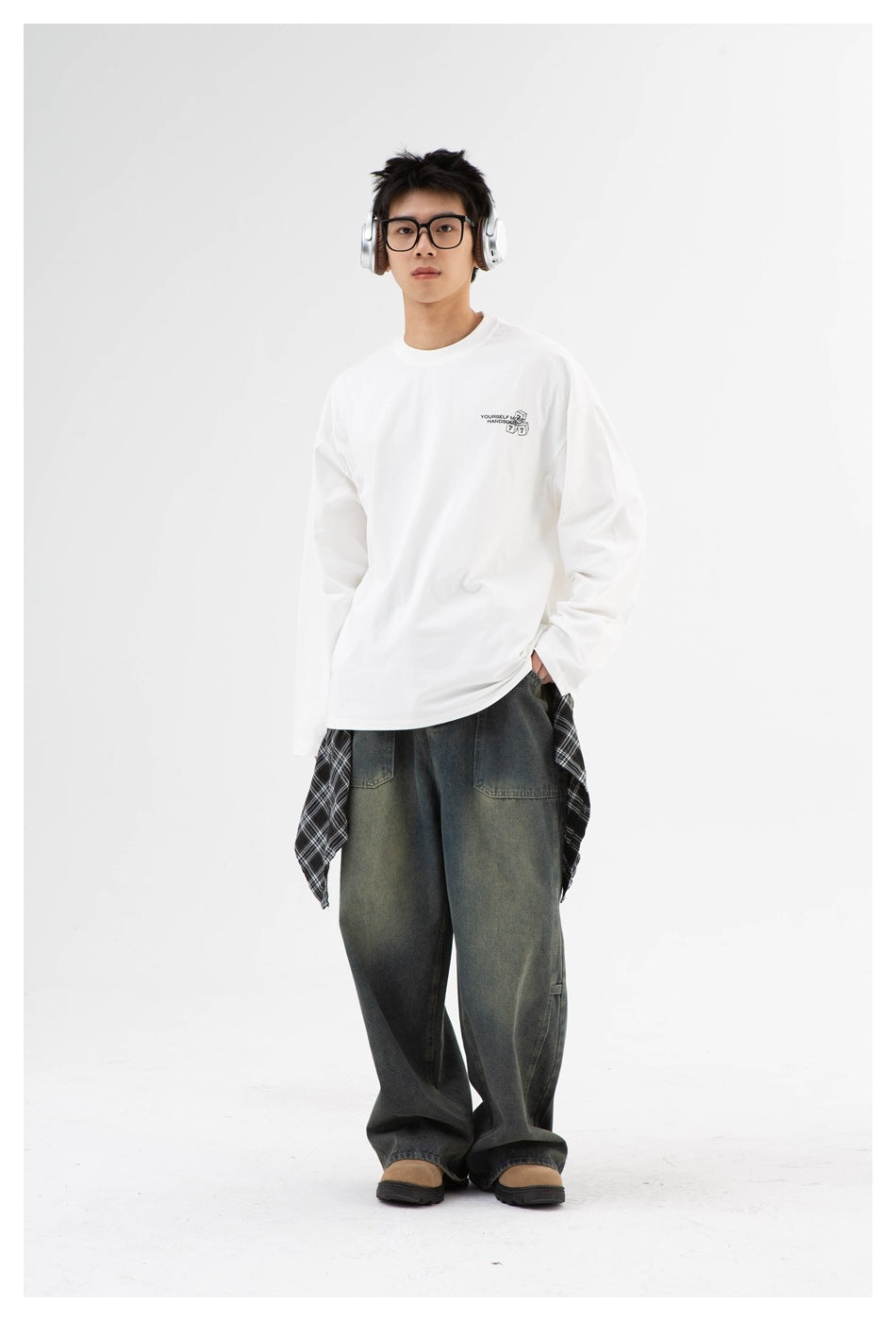 Model facing front in a white oversized long-sleeve crew-neck tee with small dice print, worn with wide-leg jeans