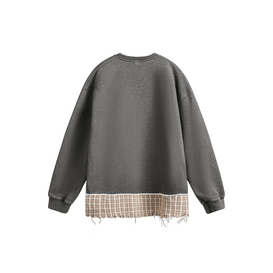 Back view of a charcoal gray sweatshirt with a long beige plaid panel and frayed hem.