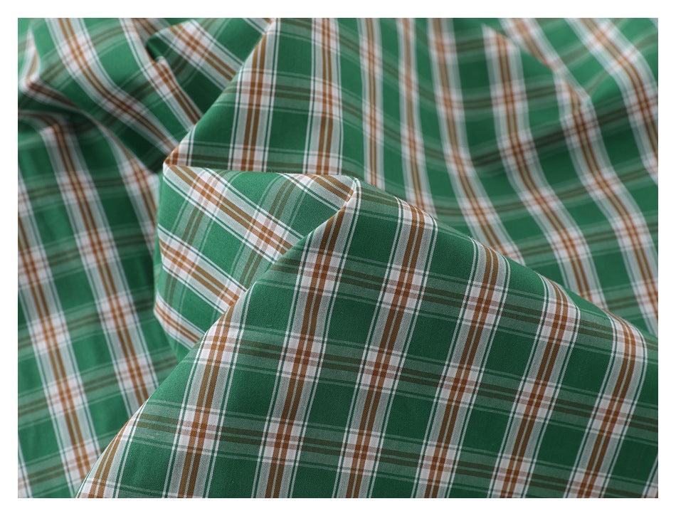 Close-up of green plaid fabric with white, tan, and dark green stripes.