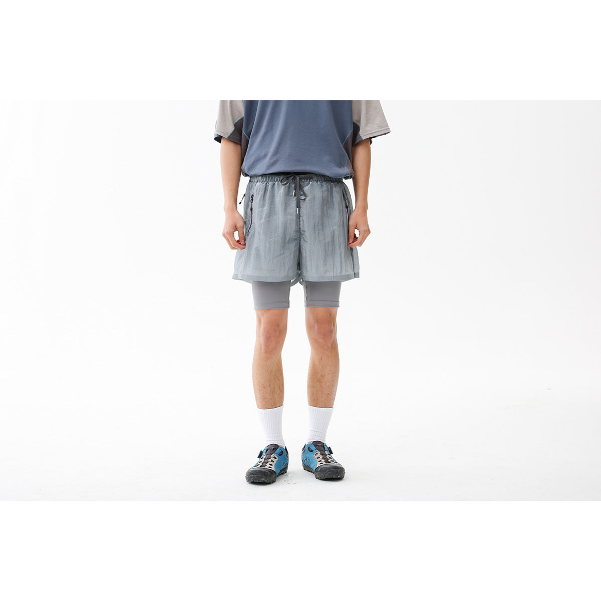 Front view of a person wearing light gray-blue running shorts over gray compression shorts.