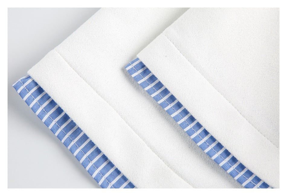 Close-up of white garment edges with blue-and-white striped trim visible along the seams.
