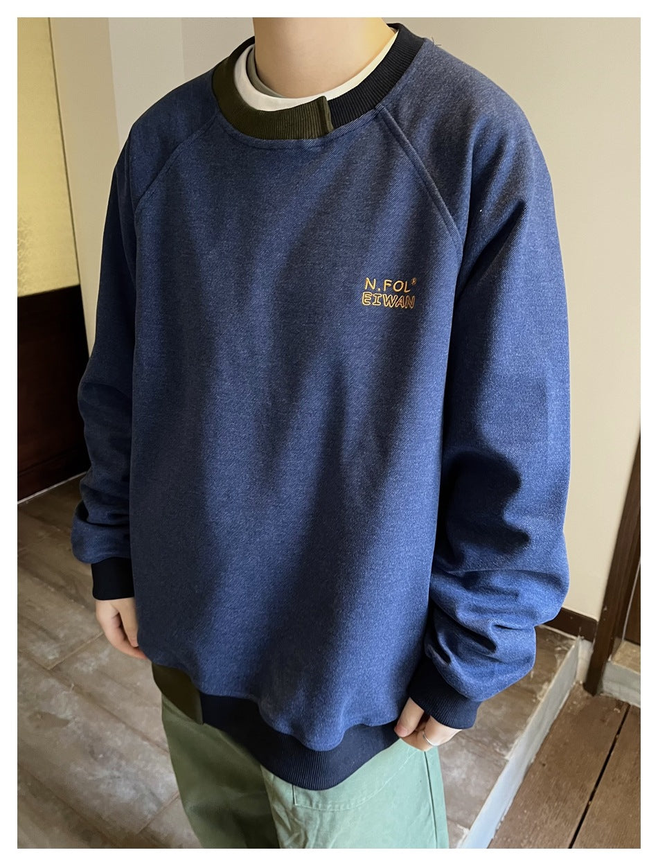 Person wearing a blue raglan crewneck sweatshirt with contrast ribbed collar and hem over green pants, front view