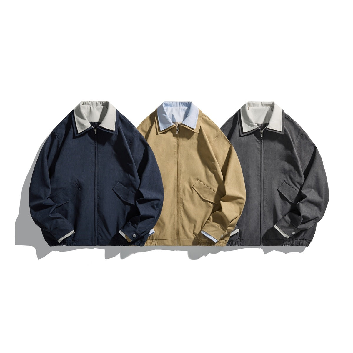 Three front views of zip-front jackets in navy, tan, and charcoal, each with a contrasting light collar.