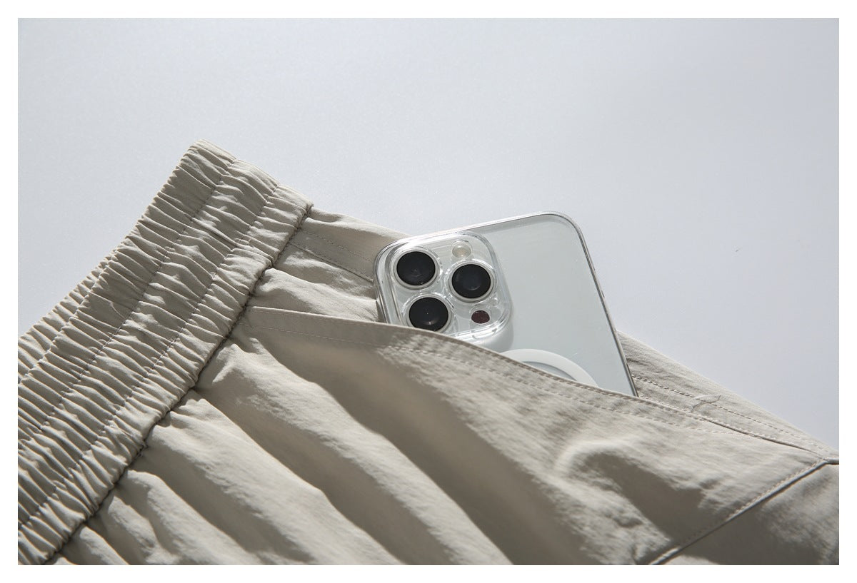 Close-up of a phone tucked into a large pocket on light beige shorts.